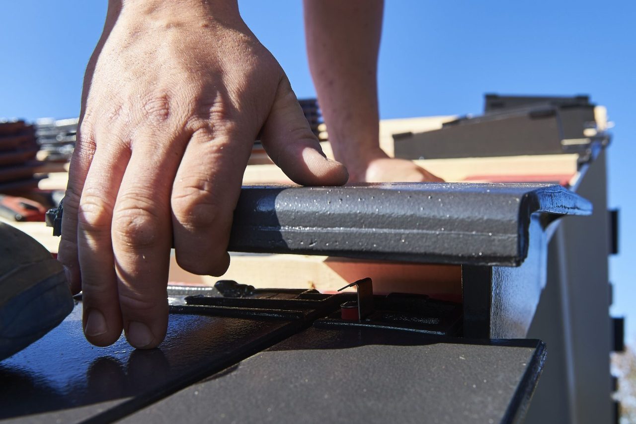 A close-up of a roofer mounting a tile