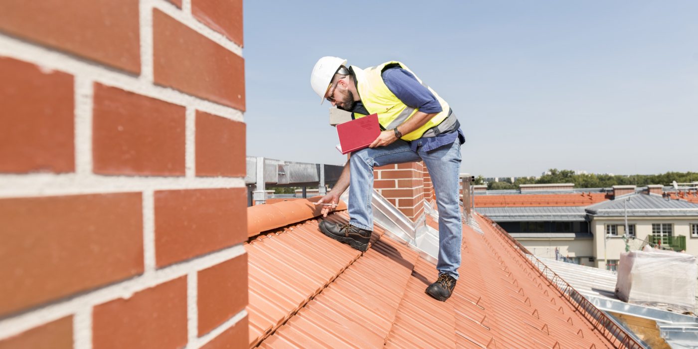 Urban roofer product manager checking ridge system wearing safety jacket and hard hat in an urban location